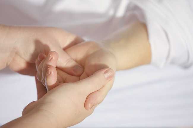 A physiotherapist assessing a patient’s hand and wrist.