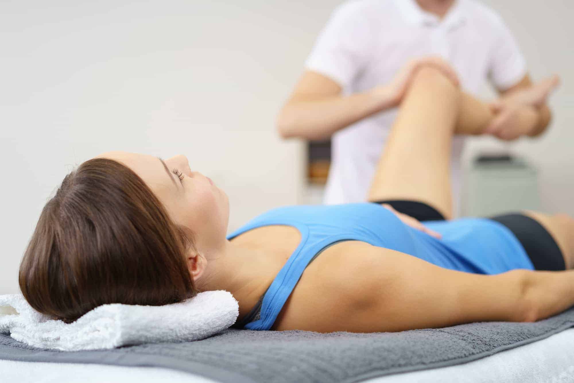 Woman with mobile physiotherapist working on her knee at home