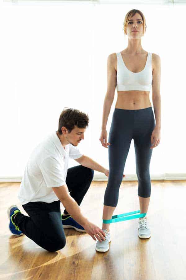 Young-physiotherapist-giving-advice-his-female-patient-during-body-training-in-a-physiotherapy-room