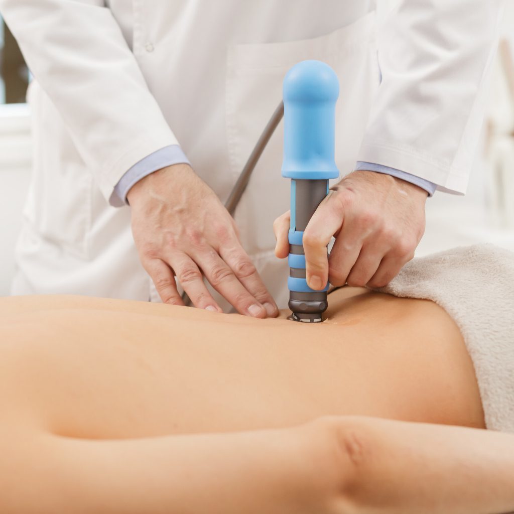 shockwave therapy being preformed on womans lower back by chiropractor