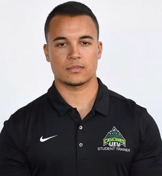 A man with short hair, wearing a black Nike polo shirt with a "UFV Cascades Student Trainer" logo, poses against a white background for "Our Team" section.