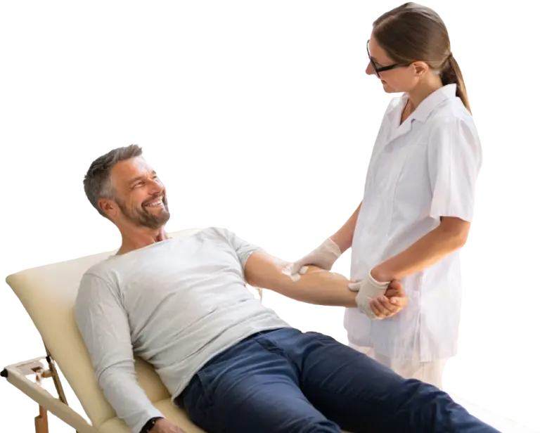 A man lying on a reclined chair smiles at a healthcare professional in North Vancouver as they prepare his arm for IV therapy.