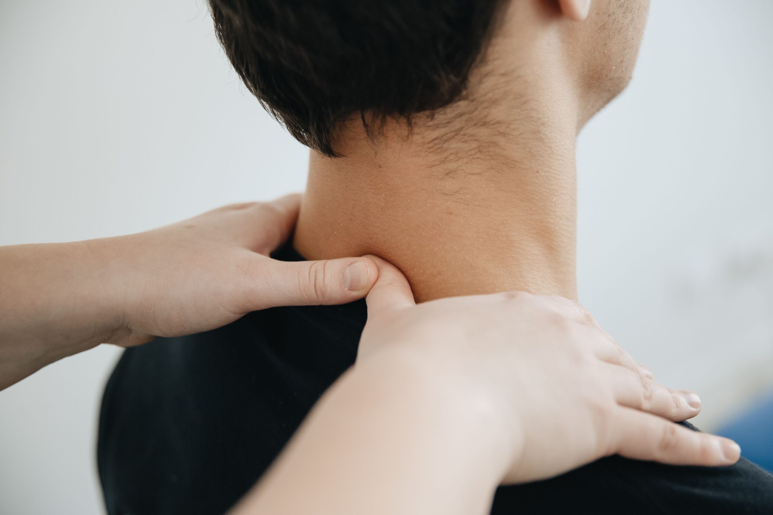 A person receives a neck and shoulder massage from another individual, with hands pressing on the muscles to help relieve chronic pain—an approach often used in physiotherapy clinics in North Vancouver.
