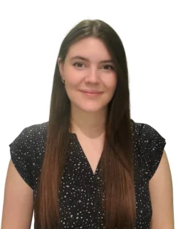 A chiropractor from Vancouver with long brown hair is smiling in front of a white background.